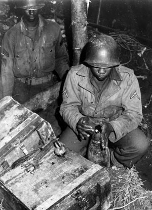 An artilleryman of the 333rd sets the fuse of a 155mm round near Schlausenbach, Germany, October 1944.