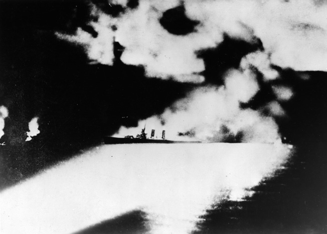 Apparently down by the stern, the cruiser USS Quincy is illuminated by Japanese searchlight beams and pummeled by accurate torpedo and shellfire. The Quincy was one of four Allied cruisers lost at Savo Island, with the Astoria the last to sink.