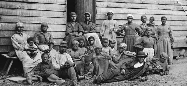 A large group of “contraband” slaves rests at a plantation near Pamunkey Run, Virginia, after escaping captivity. 