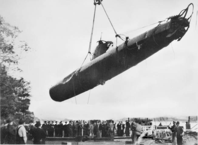 A crowd of onlookers gathers to witness the lifting of one of the Japanese midget submarines from its watery grave in Sydney Harbor. The bodies of two Japanese crewmen were found in this craft and another sub that was recovered. 