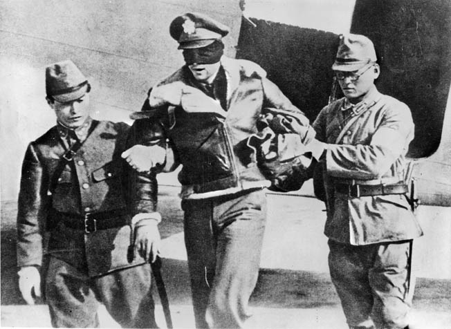 Japanese guards transport blindfolded Lieutenant Robert L. Hite, co-pilot of Plane 16, to a POW camp in China. The pilot, Lieutenant William Farrow, was executed by the Japanese.