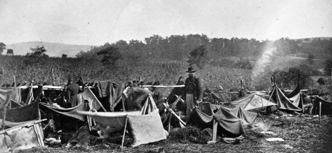 A Union doctor from the 14th Indiana Volunteers tends to Confederate wounded after the Battle of Antietam in September 1862. Blankets stretched over fence railings were the only protection from the elements at this crude medical aid shelter.