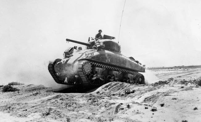 An M4 Sherman tank rumbles over a sand dune in the Tunisian desert. Bromberg faced off against a German tank for the first time during the drive across the desert in 1943.