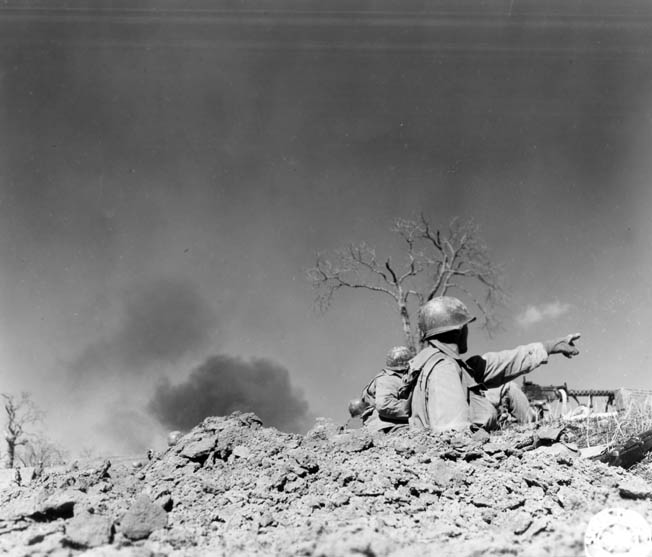 A mountain trooper points out a German position to a .30-caliber machine-gun crew near Mount Della Vedetta, March 3, 1945.