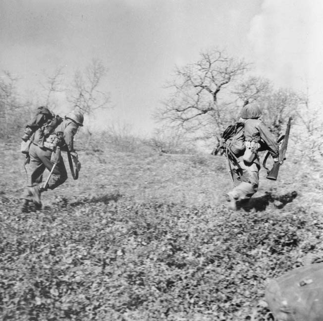 Two soldiers from the 86th Mountain Infantry Regiment dash over a hill during the first day of Operation Craftsman, April 14, 1945. 