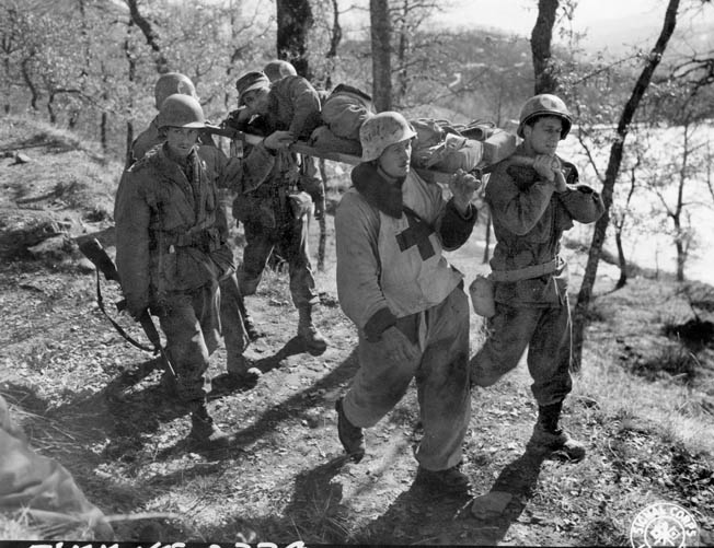 A captured German medic and a second German in back, helped by men from the 10th, carry a wounded comrade to an American aid station after the battle for Mount Belvedere, February 20, 1945. 