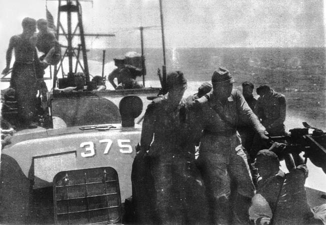 With Hank Blake at the wheel in PT-375’s cockpit, the Japanese surrender delegation (foreground) is treated to a “rough ride” in choppy seas, bracing themselves with the gun mount and ready box, September 8, 1945.