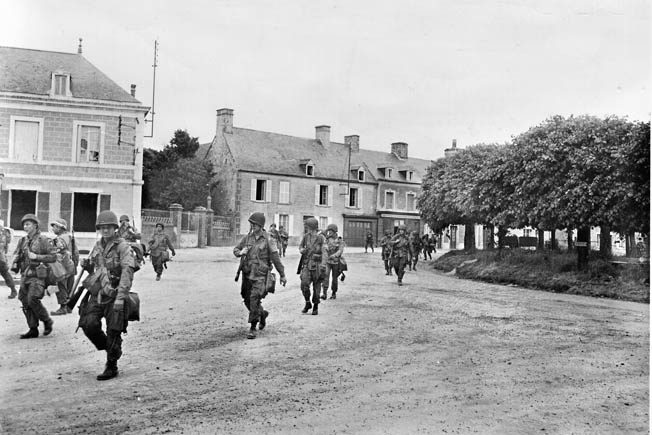 Men of the 101st Airborne march through Ste. Marie-du-Mont on their way south Carentan.