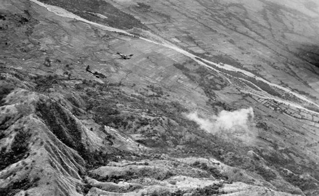 With white phosphorous shells marking the target, two Marine Corps SBD dive bombers prepare to work over Japanese positions in the Philippines.