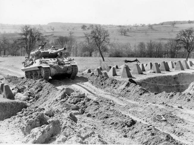 An American tank destroyer maneuvers through the Dragon’s Teeth of the Siegfried Line at the German border. The last line of defense included tank traps, pill boxes, and bunkers. Fighting became more intense east of the border. 