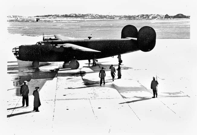 Prior to its departure with rescued Allied airmen and Norwegian resistance fighters aboard, a “Sonnie” B-24 Liberator sits on an airfield at Goteborg, Sweden, while a Swedish soldier stands guard.