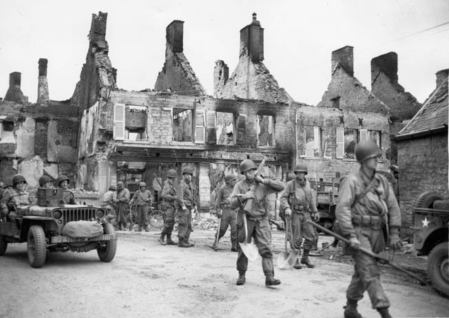 American infantrymen move through a bombed-out French town. While in Caumont, Puhalovich’s half-track was strafed by a German plane and blown up.