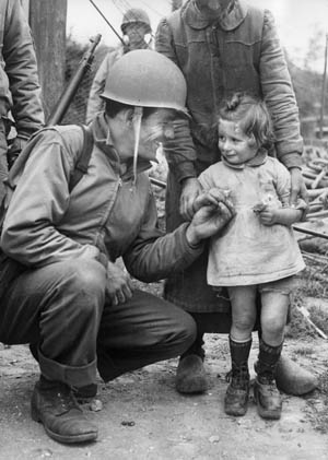 A friendly GI gives a piece of candy to a French girl. Puhalovich also gave candy to a little girl and was thanked with a flower.