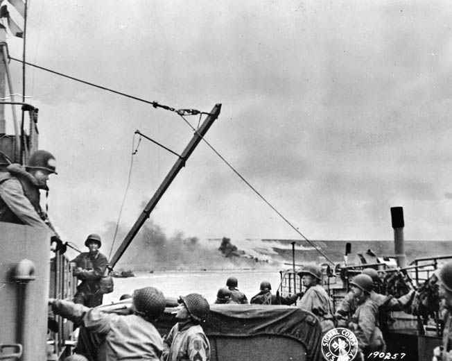 A Landing Craft Tank, full of vehicles, equipment, and troops of the Big Red One, heads toward smoke-shrouded Omaha Beach, Normandy, during the D-Day landings, 6 June 1944. 