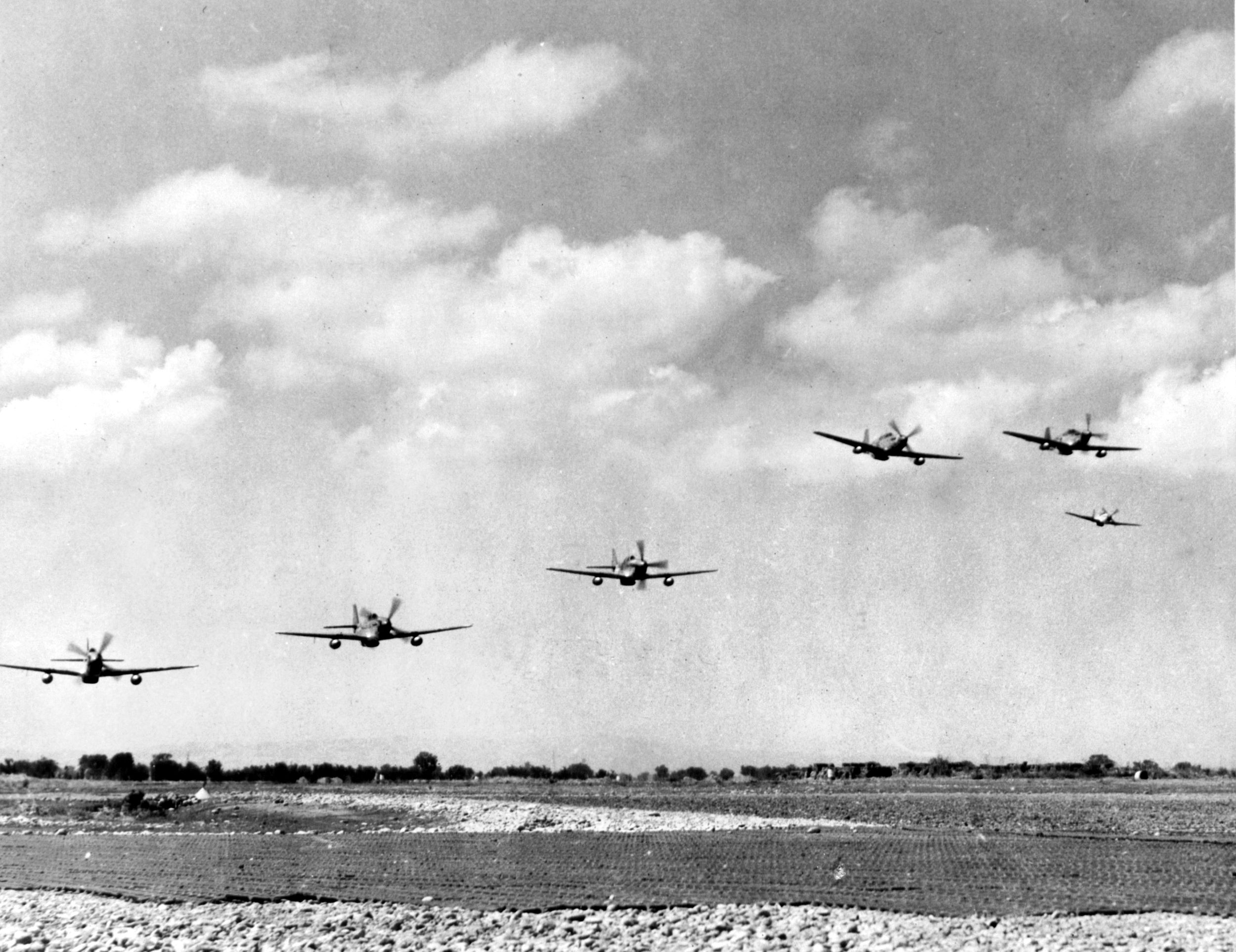 Equipped with wing tanks for a long-range mission over Germany, P-51 Mustangs of the 332nd Fighter Group buzz their base at Ramitelli, Italy.