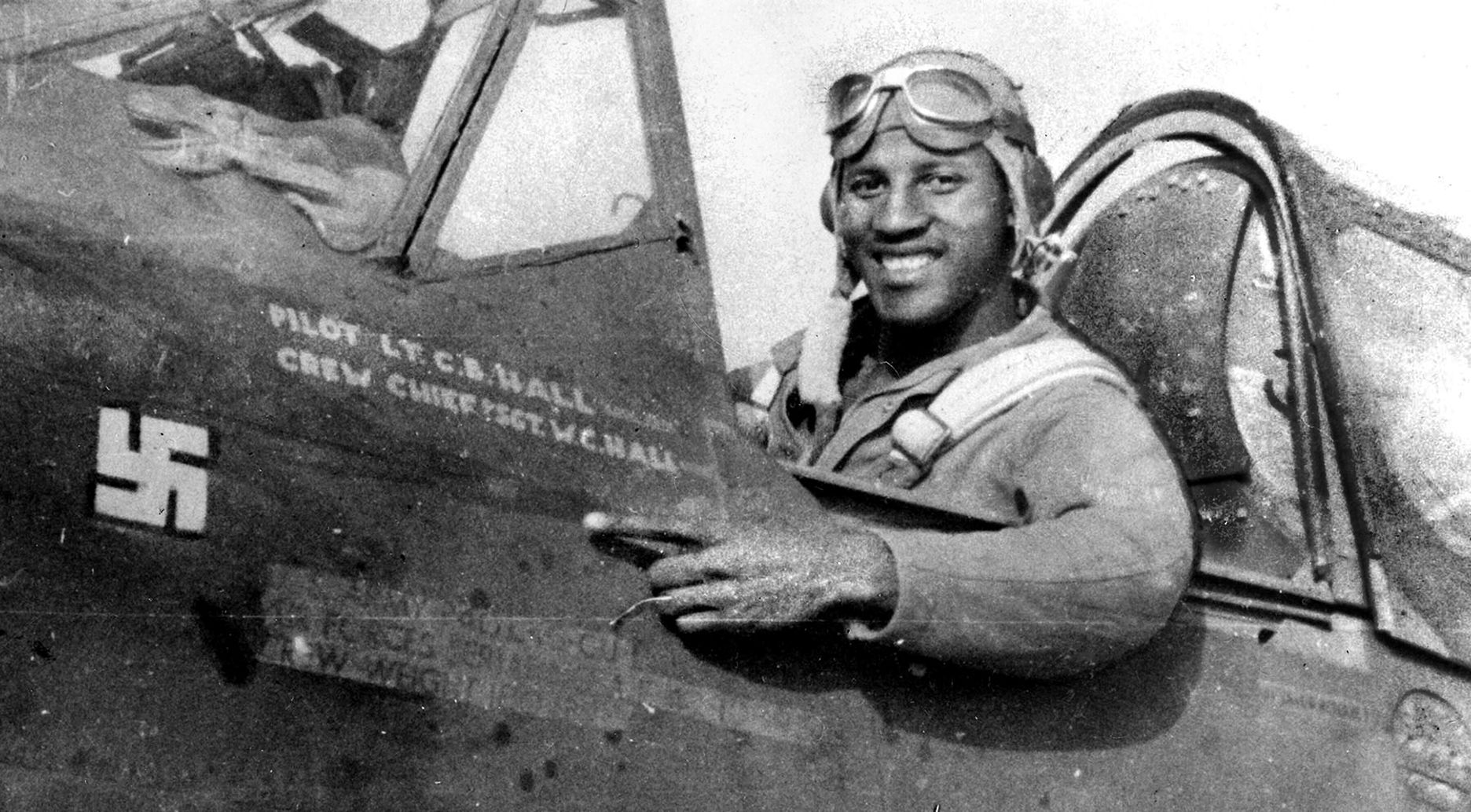 First Lt. Charles B. Hall, in the cockpit of his Curtiss-Wright P-40L Warhawk fighter, points to the swastika that represents a Luftwaffe Fw 190 he shot down on July 2, 1943, over Pantelleria. Hall was the first pilot of the 99th to down an enemy plane. 