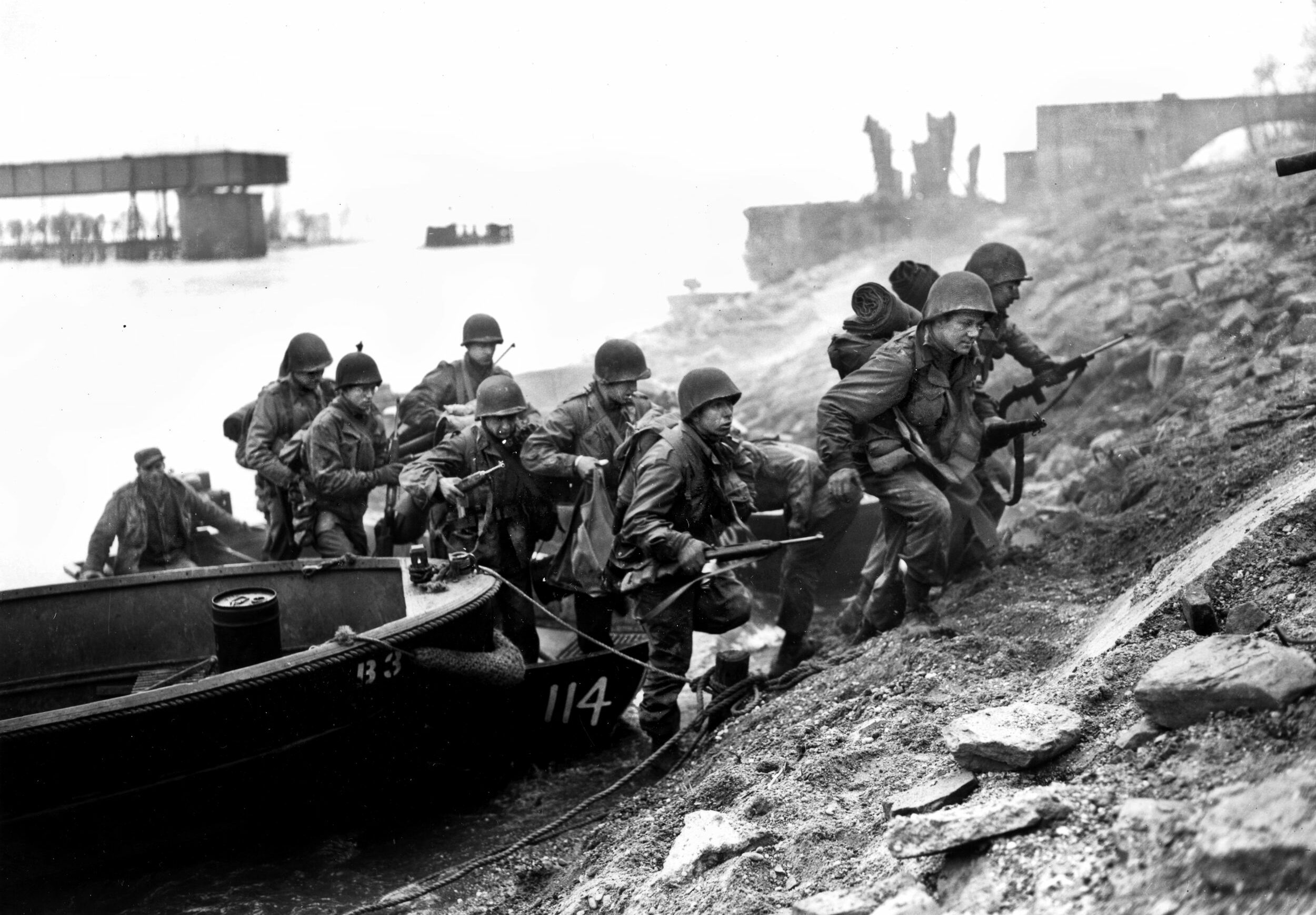 With a destroyed railroad bridge behind them, 3rd Infantry Division troops scramble from their assault boats onto the eastern bank of the river. Enemy opposition varied in intensity
