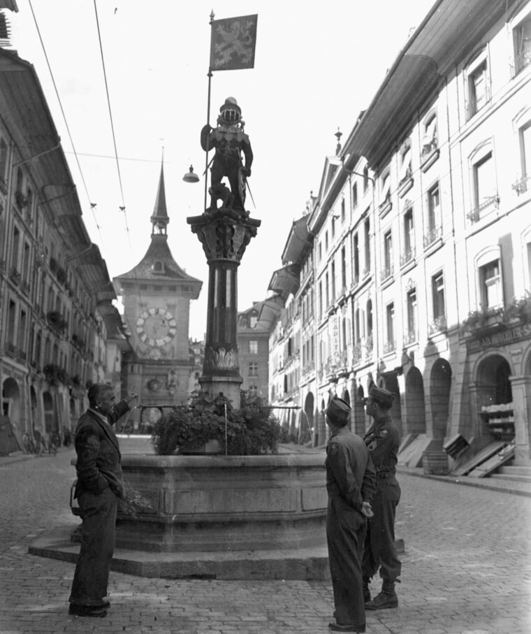 A Swiss guide points out one of many historic sites in the city of Bern to two servicemen.