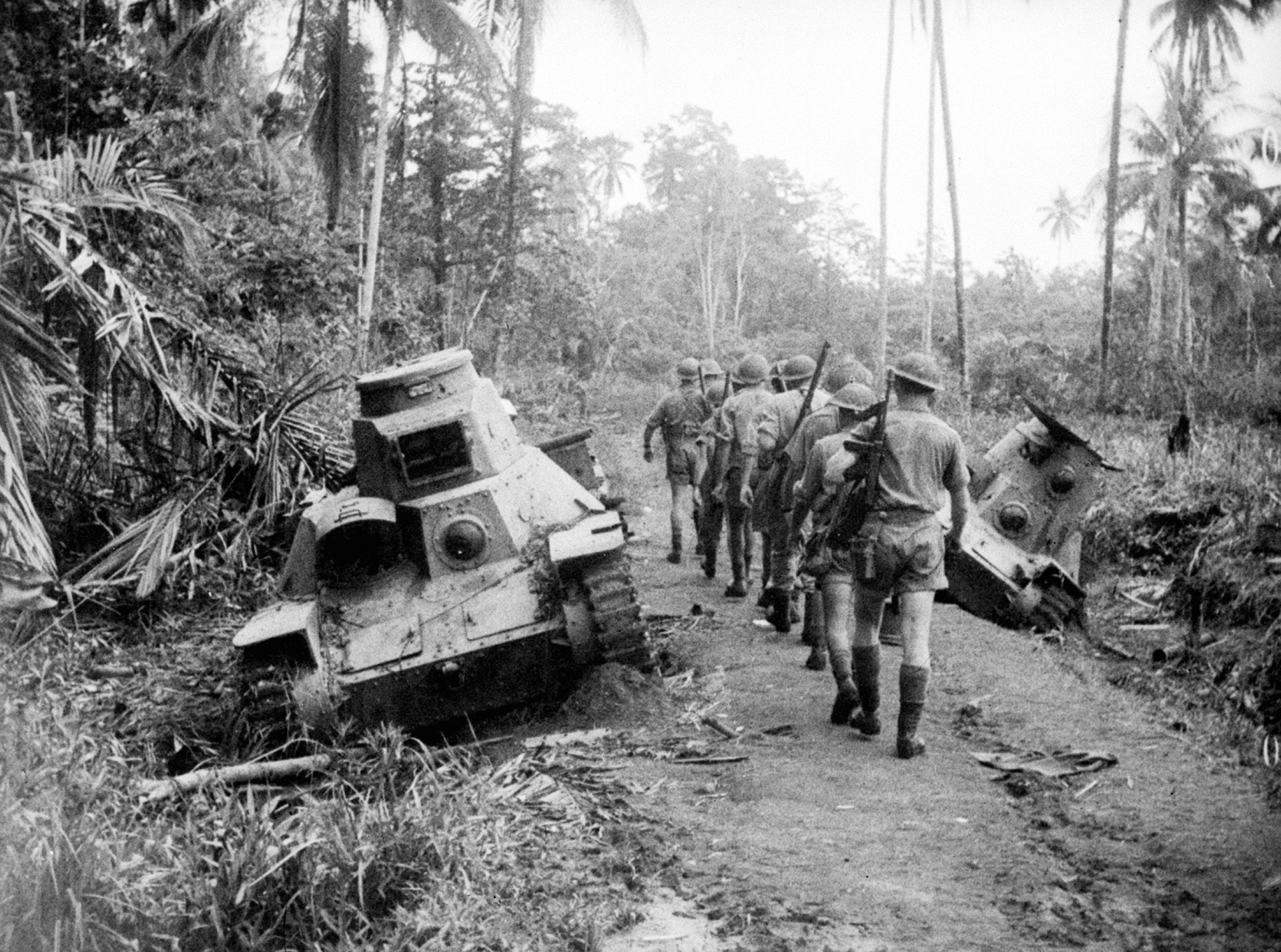 Australian infantrymen pass the wreckage of several Japanese 95 HA-GO light tanks destroyed in an earlier engagement.