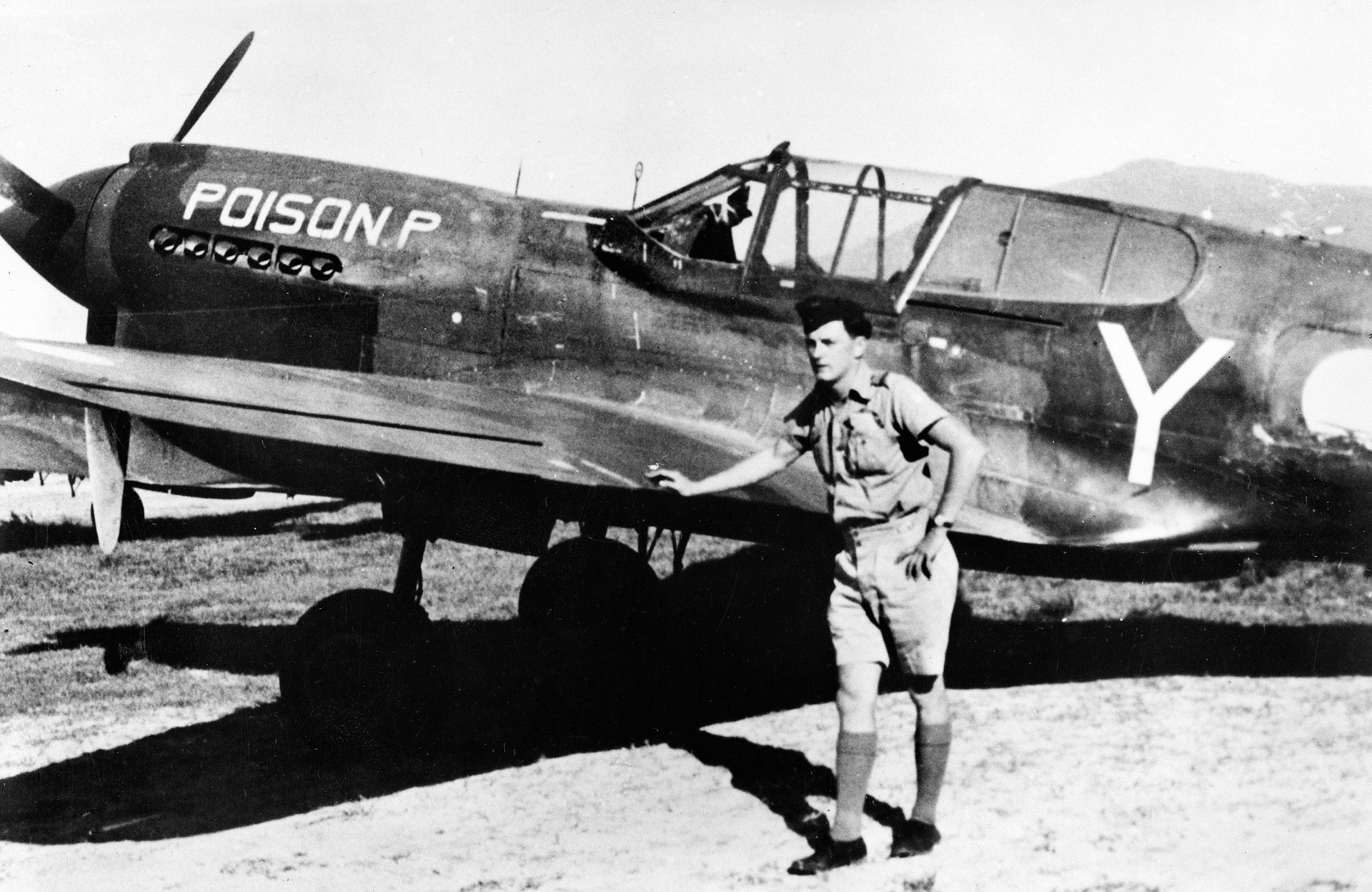 Flying Officer Peter A. Masters poses in front of his RAAF 75 Squadron Kittyhawk fighter dubbed  “Poison P.”