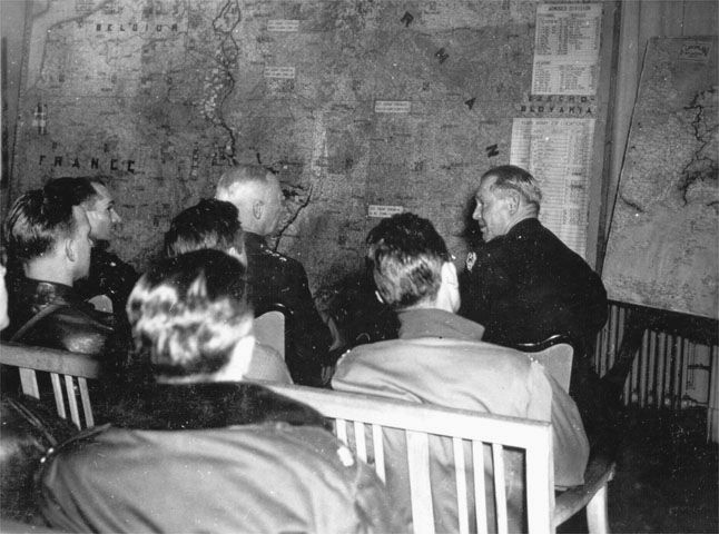 General George S. Patton Jr., commander of the U.S. Third Army, sits at center during a briefing at XIX Tactical Air Command. Seated with Patton are General Homer Sanders, commander of the 100th Fighter Wing, and Major General Otto P. Weyland, commander of XIX TAC.