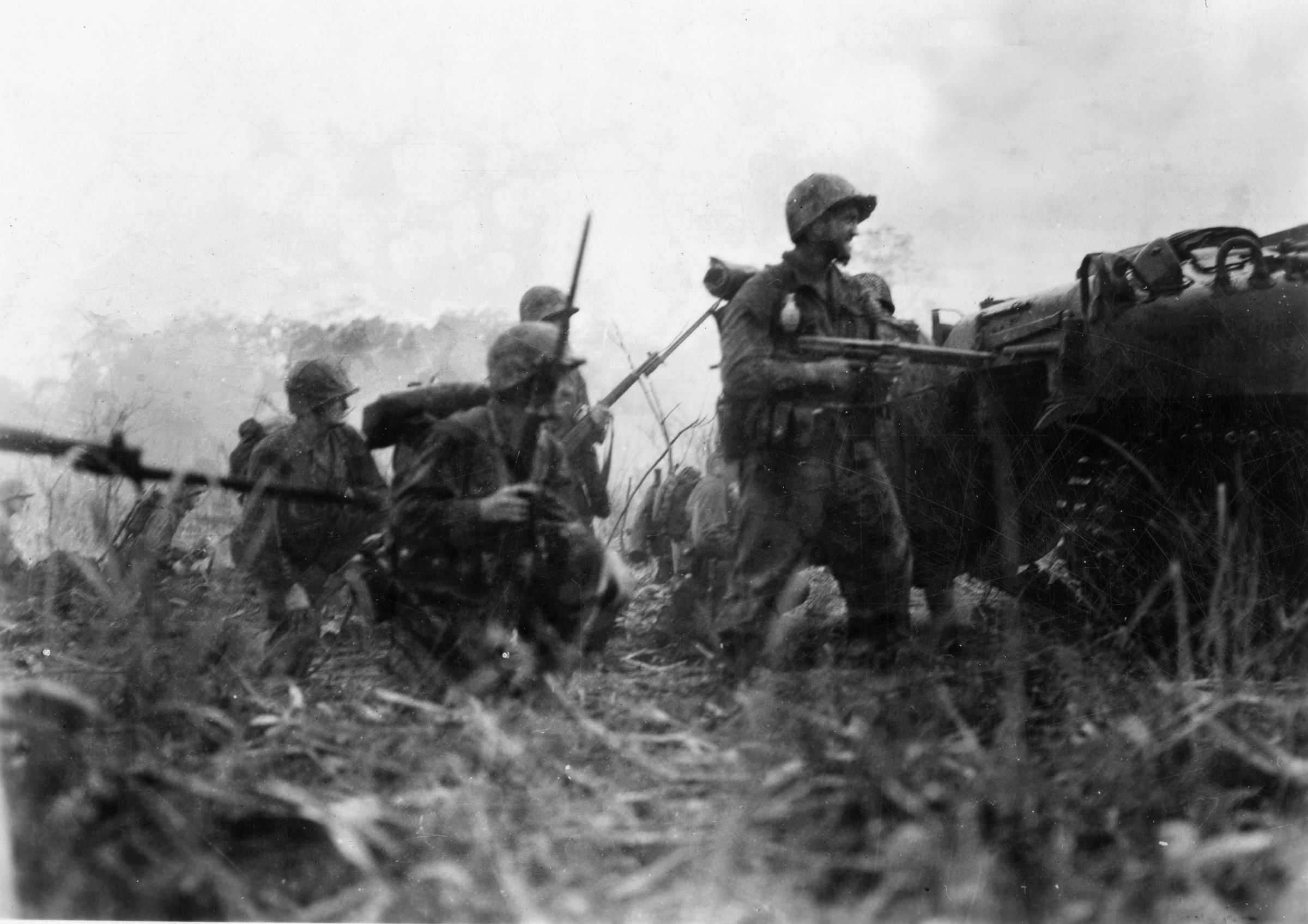 Thick jungle and heavy rains impeded the American advance at Cape Gloucester. However, tanks were employed despite the deplorable conditions and rugged terrain. Here, a group of advancing Marines is covered by a tank that uses its .50-caliber machine gun for suppressing fire.