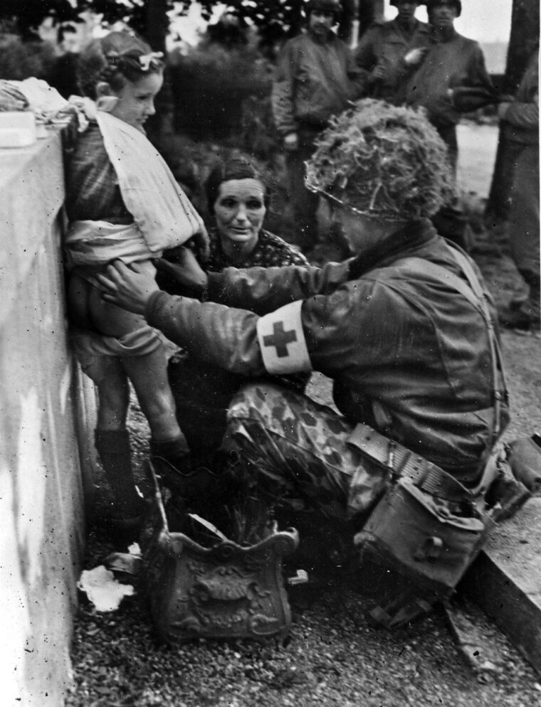 A medic dresses a small girl’s wounds as her mother looks on. 