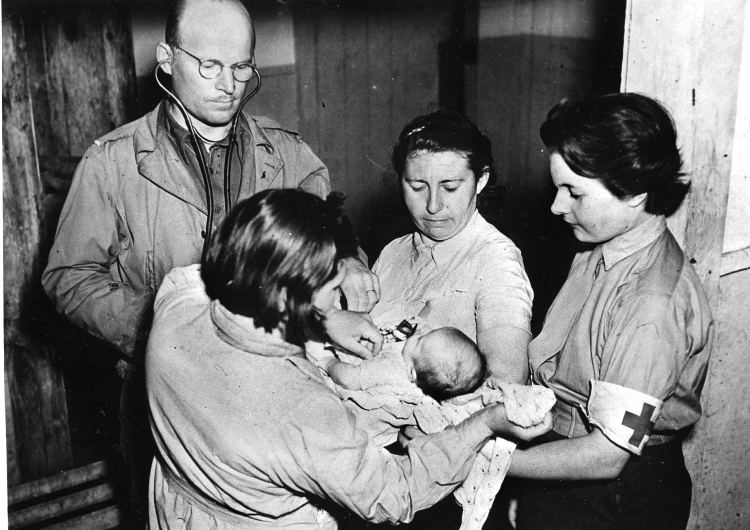 A truly Allied medical team tends to a French baby. The doctor is an American, the nurse in the center is a former Russian surgeon who was captured by the Germans in Leningrad, and the nurse on the right is a Swiss member of the French Army.