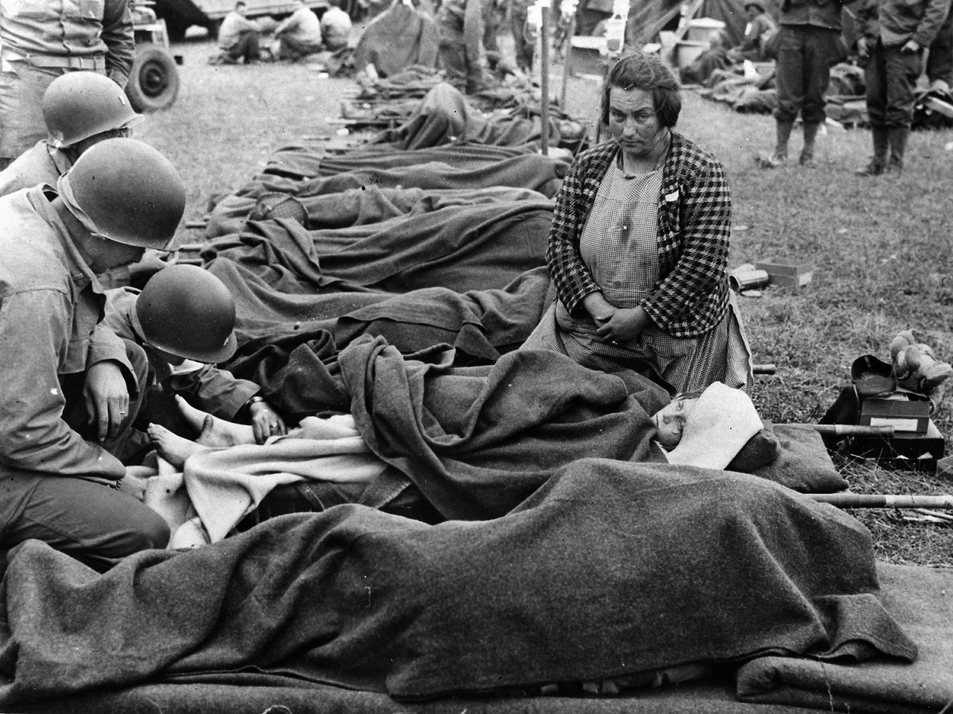 American medics treat a girl while her worried mother kneels by her side.