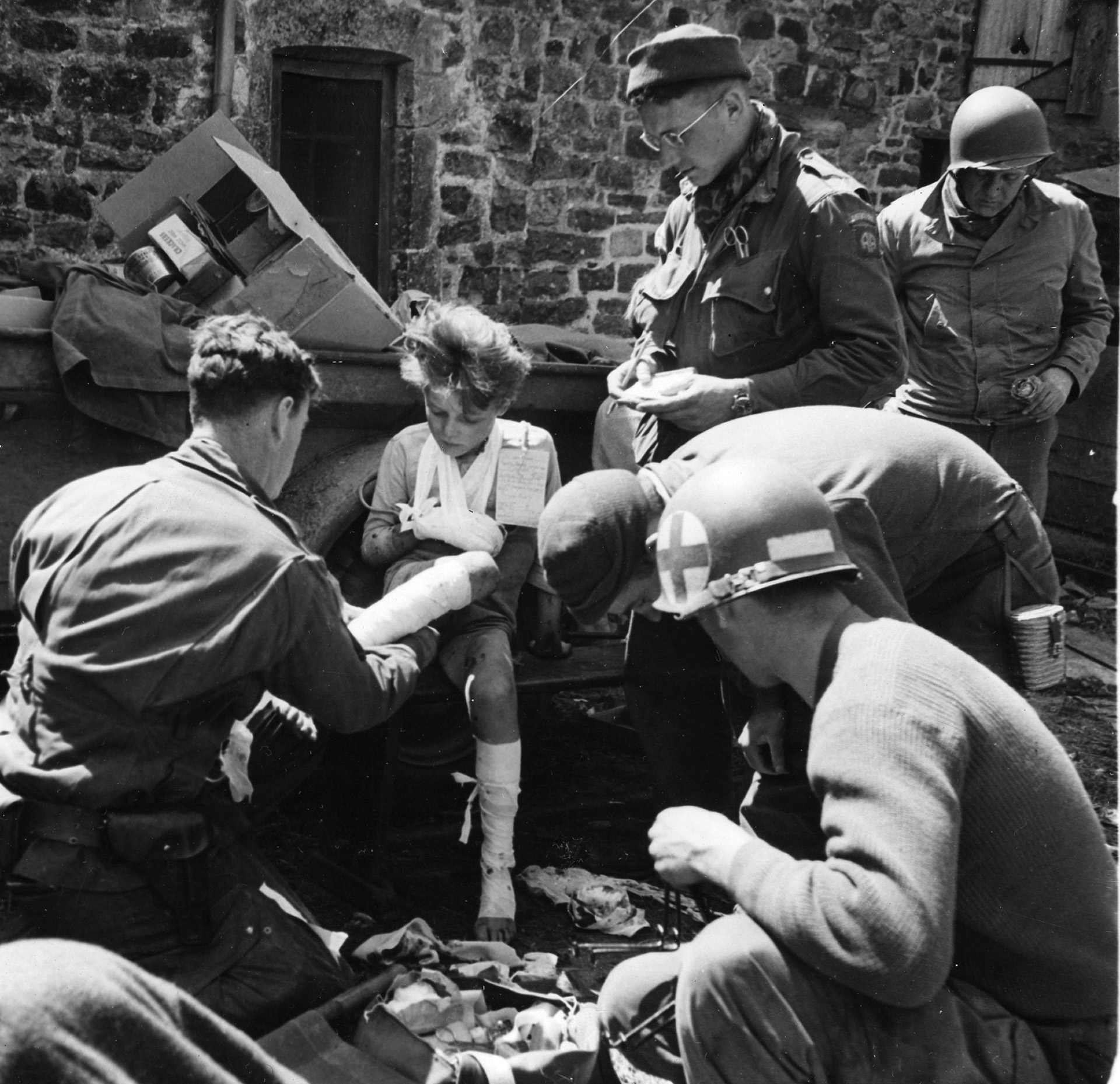 Ten-year-old Jean Louis receives first aid from American airborne medics after the fighting at St. Sauveur.