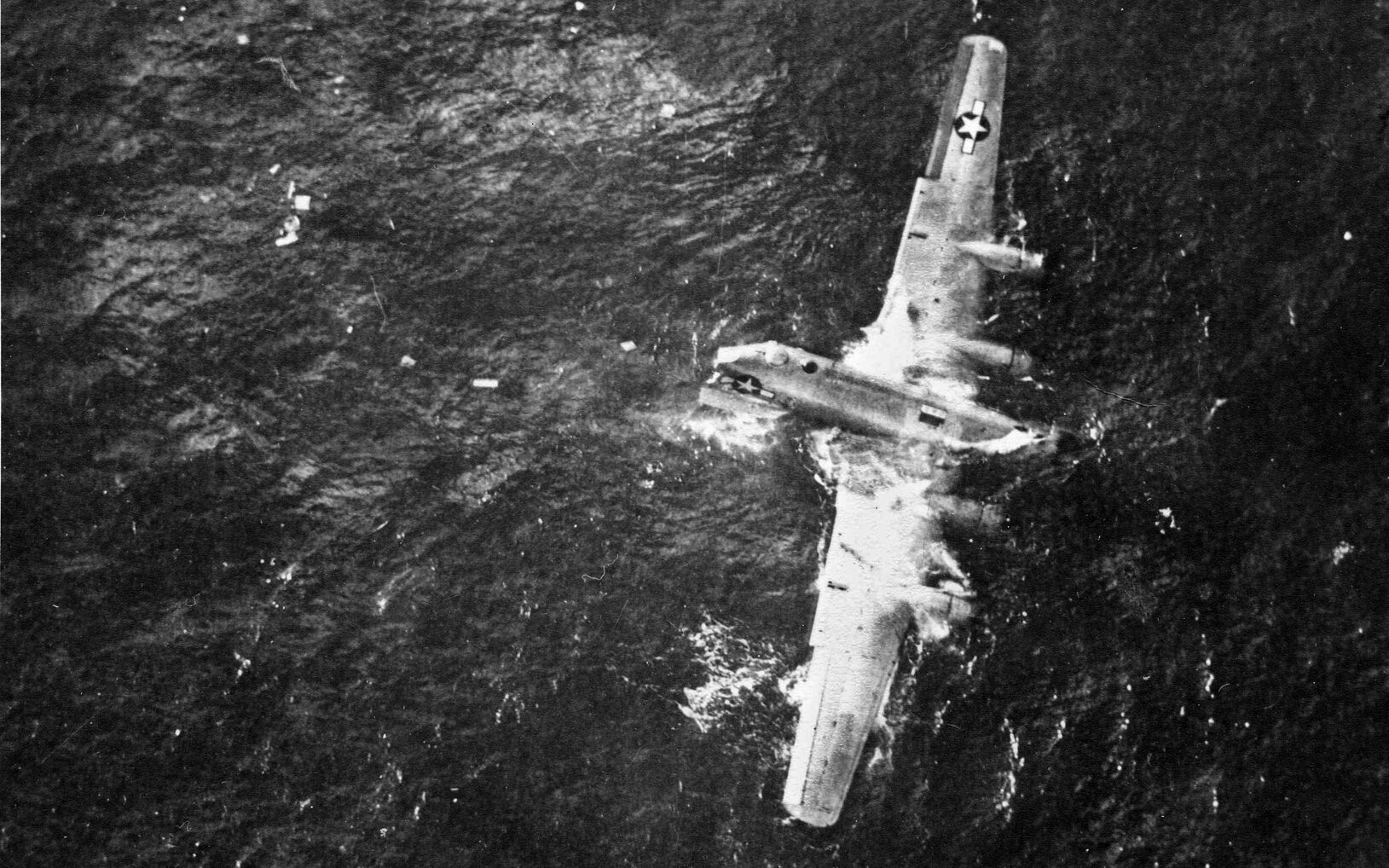Not all the raiders escaped scot-free. Here half a B-29 that ditched in the sea remains afloat with a surviving crew member clinging to the No. 1 engine at top. 