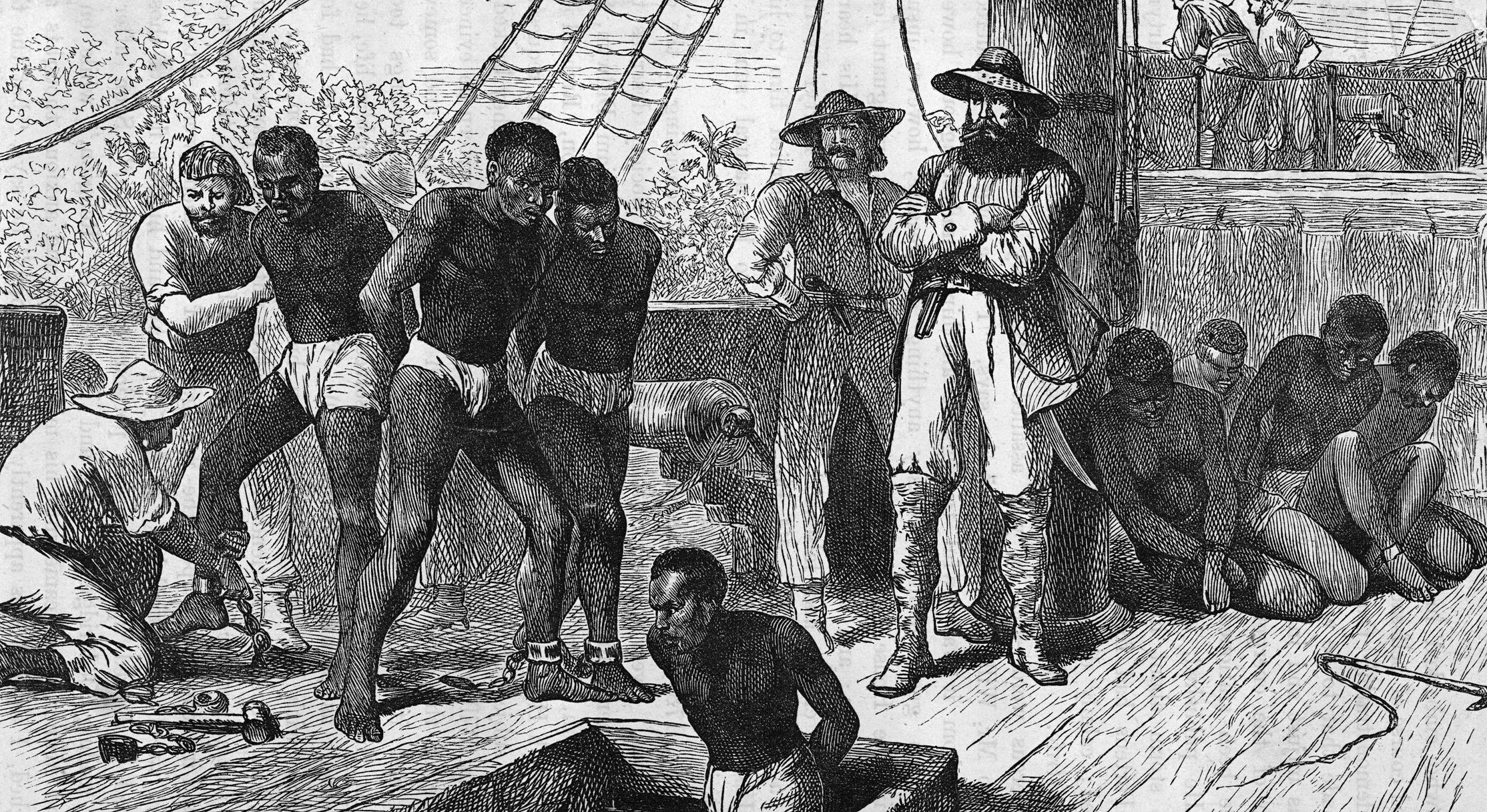African slaves are loaded aboard ship for the grim voyage across the Atlantic. The ship’s captain, pistol in his belt, watches as crewmen handcuff and shackle the slaves before sending them below deck. More bound slaves cower behind him.