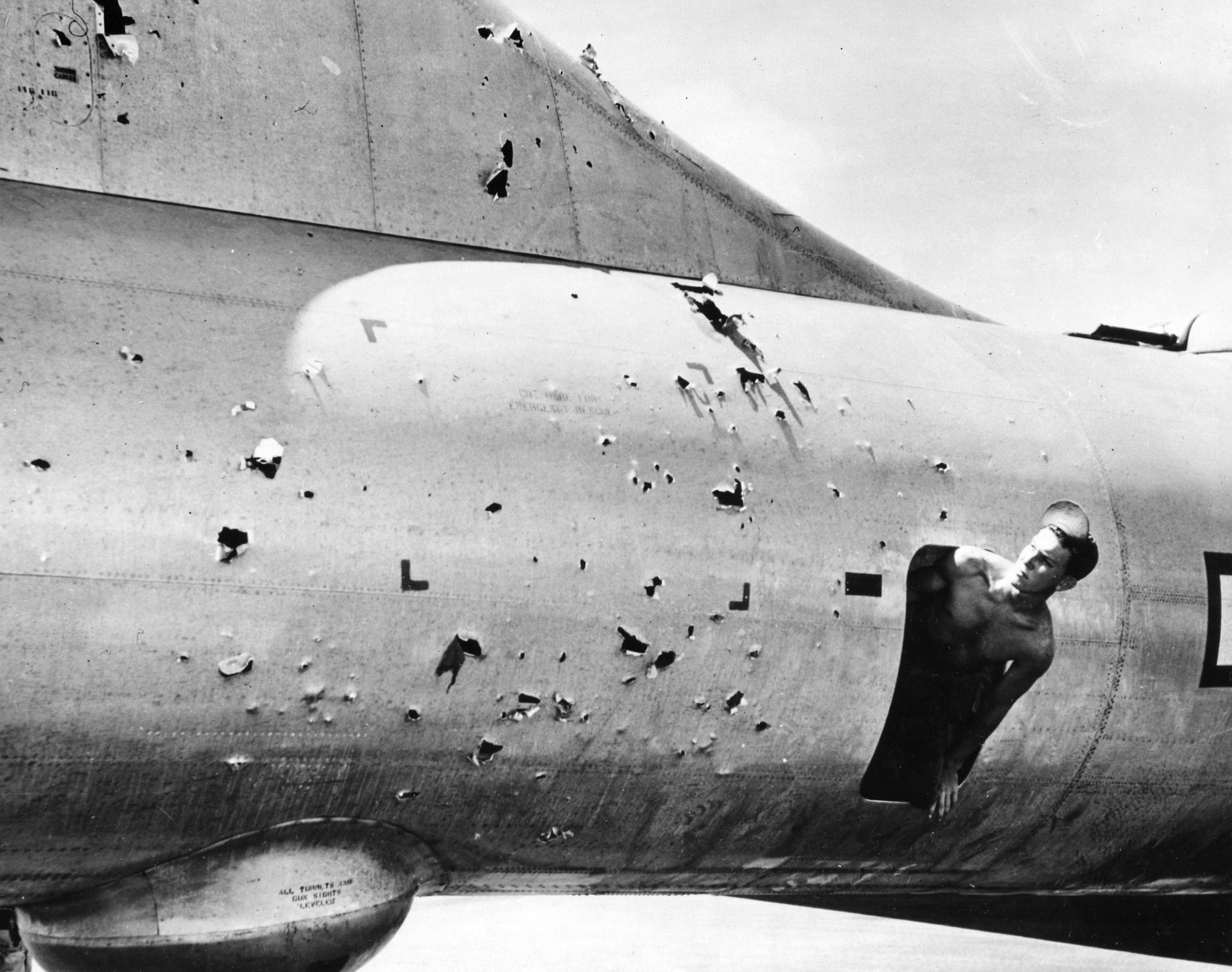 A crew member surveys the damage to his B-29 caused by Japanese flak guns during an April 1945 raid on the Japanese capital.