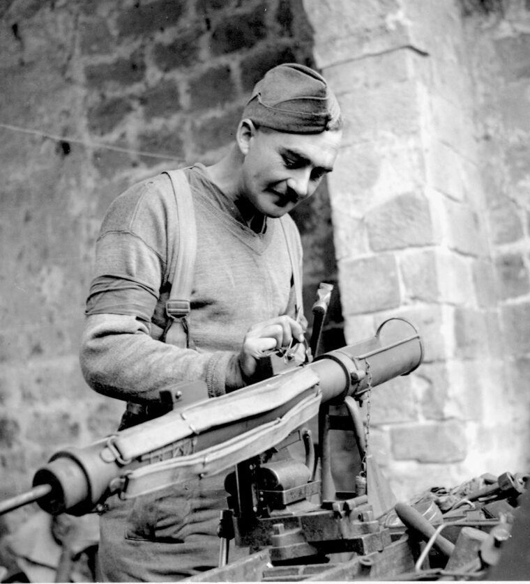 An armorer performs maintenance on the predominant antitank weapon among British troops, the PIAT.