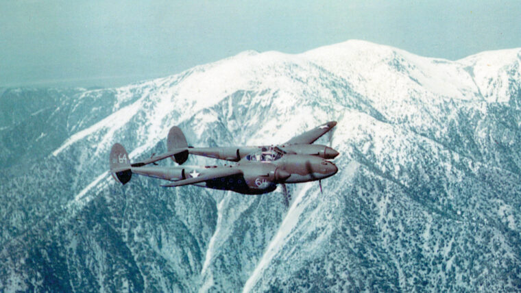 A twin-boomed P-38 Lightning flies over snow-capped mountain peaks. With its tremendous range and firepower, the P-38 saw service in every major theater of World War II.