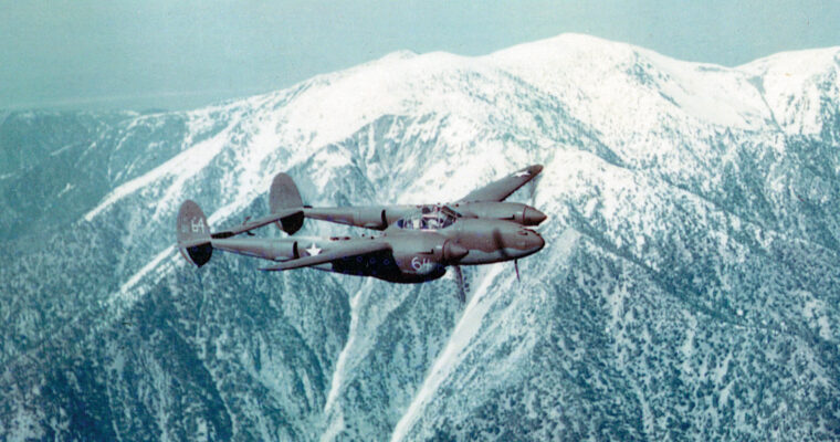 A twin-boomed P-38 Lightning flies over snow-capped mountain peaks. With its tremendous range and firepower, the P-38 saw service in every major theater of World War II.