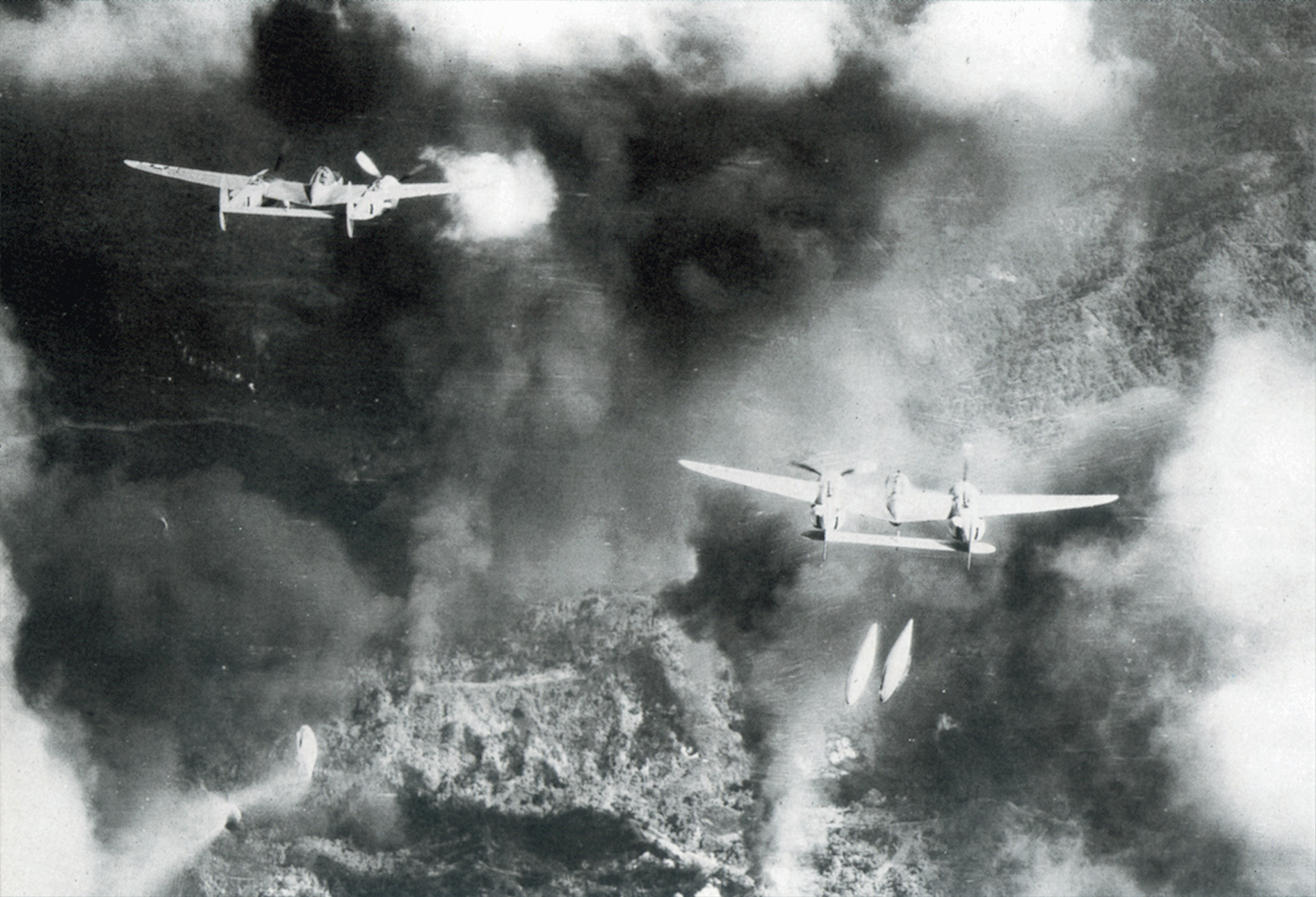 Demonstrating their versatility, P-38s execute the fighter-bomber role, dropping napalm on Japanese positions at Ipo Dam on the Philippine island of Luzon. 