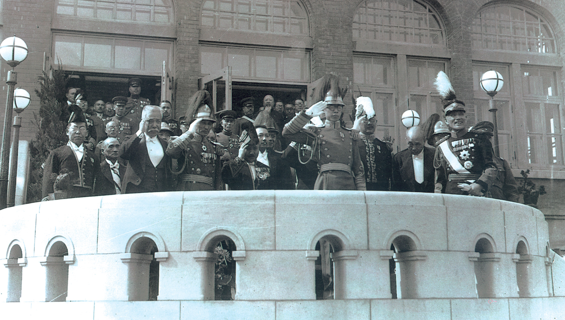 Pu Yi, wearing glasses and a plumed hat, salutes the crowd at the ceremony proclaiming him emperor of the Japanese puppet state of Manchukuo.