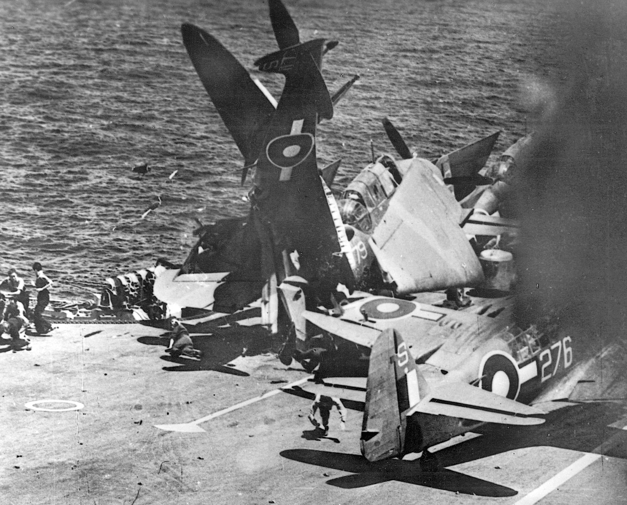 A heap of twisted steel litters the deck of a British carrier after a Spitfire crashed on landing in the Pacific, July 1945.
