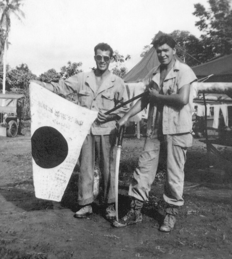 Mantini (left) displays a captured Japanese regimental flag and prized enemy sabers at Hollandia, New Guinea, in 1944.