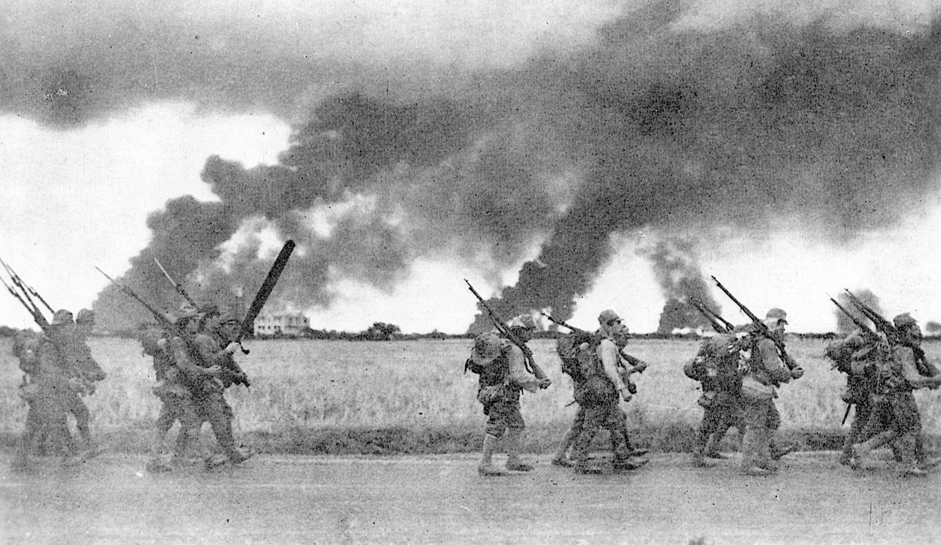 Japanese troops advance swiftly past burning installations of the American military base at Subic Bay in the Philippines.