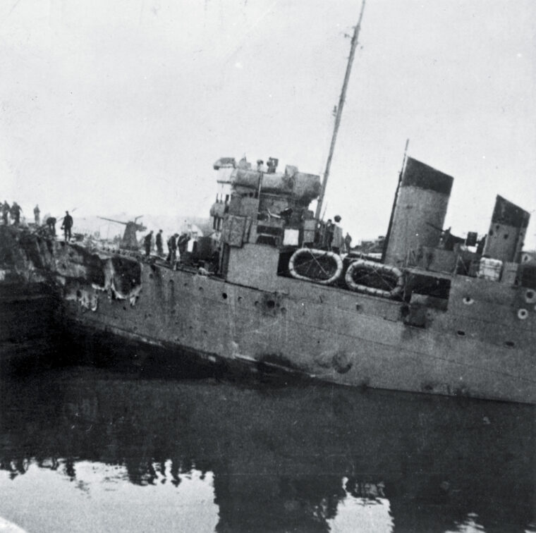 HMS Campbeltown lies wedged into the Normandie Lock at the French port of St. Nazaire on March 29, 1942. The obsolete destroyer was sacrificed during a British commando raid to disable the lock. Explosives packed into the hull did not detonate for several hours, and many of the German personnel shown inspecting the ship were killed in the blast.