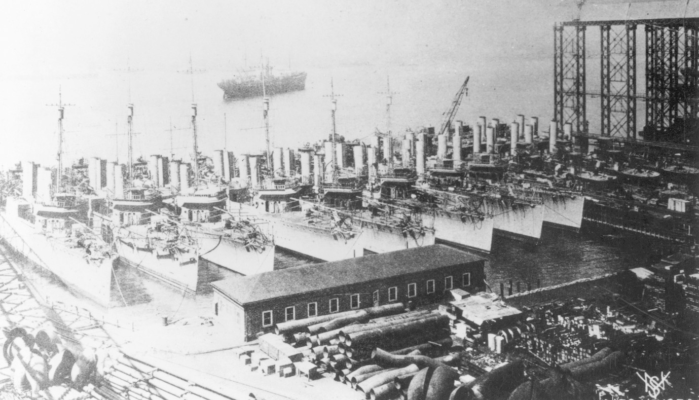 A gathering of Clemson-class destroyers lies at anchor in a shipyard. A total of 273 of these warships were commissioned from 1917-1922. They were also called “four pipers” due to their distinctive arrangement of funnels.