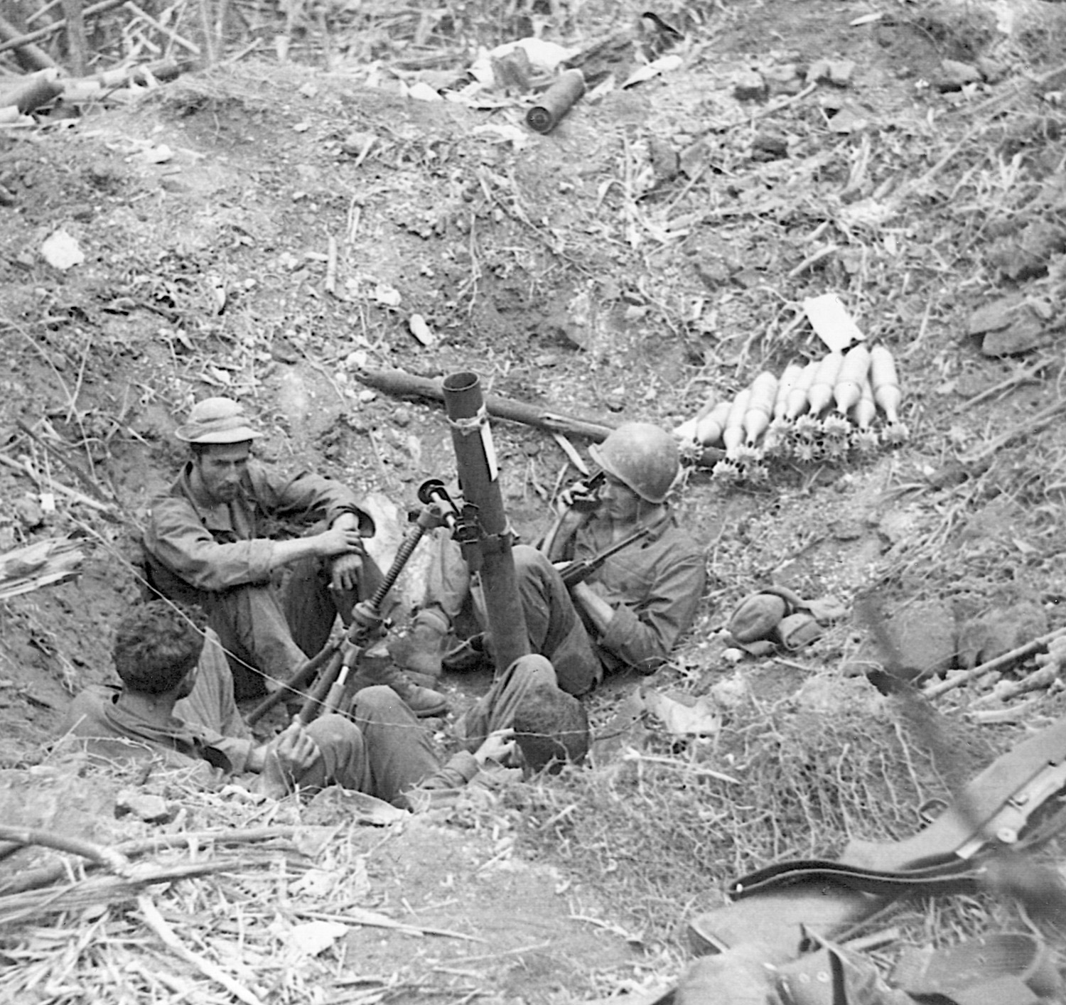 Set up in a bomb crater, the crew of an 81mm mortar awaits the order to fire on the Japanese.