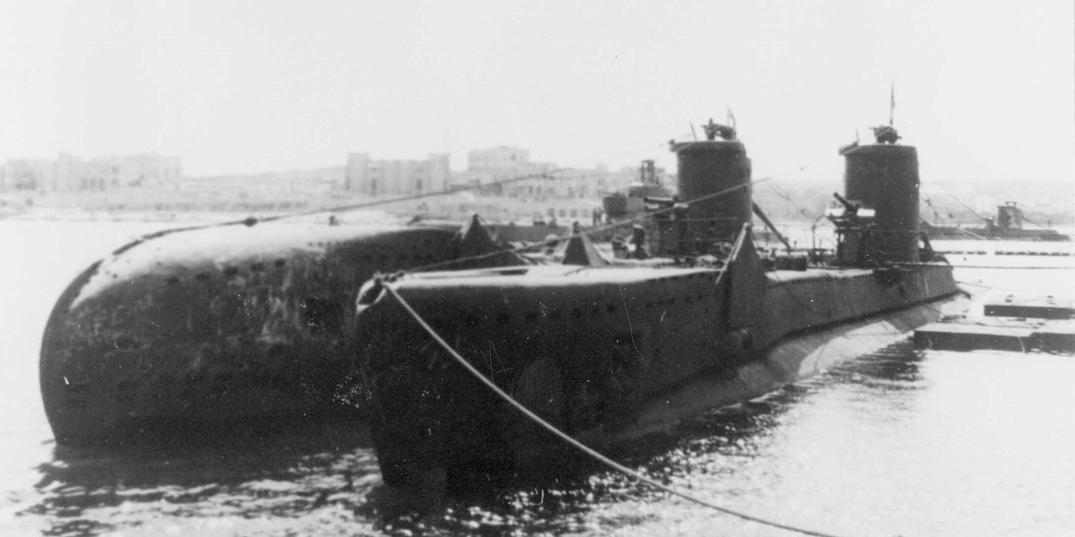 Tenth in the line of British-built U-class submarines, HMS Upholder is seen riding outboard of HMS Urge at Lazaretto. In one of only two authenticated photos of Upholder, the submarine's high bow is prominent compared to the flush bow of HMS Urge.