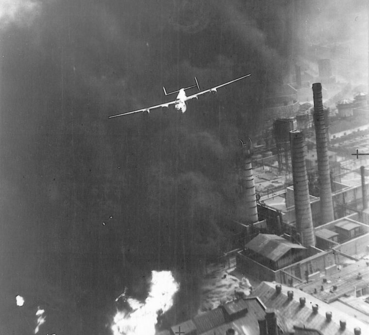In what is perhaps the most famous photograph of the low-altitude Ploesti raid, a B-24 flies through a pall of smoke from burning installations just a few feet above smokestack level. 