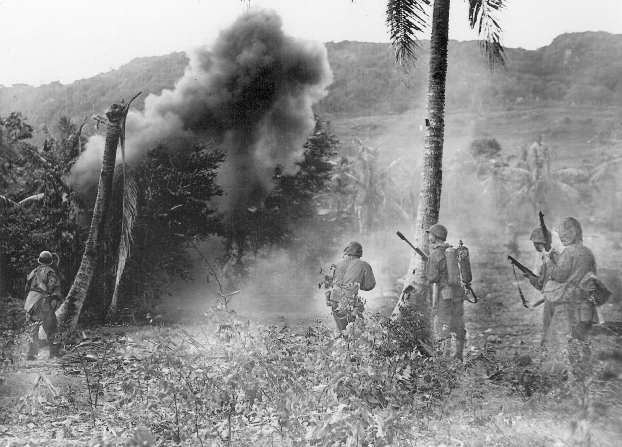Rooting Japanese defenders out of caves with demolition charges and flamethrowers, American soldiers stand ready to deal with any who emerge.