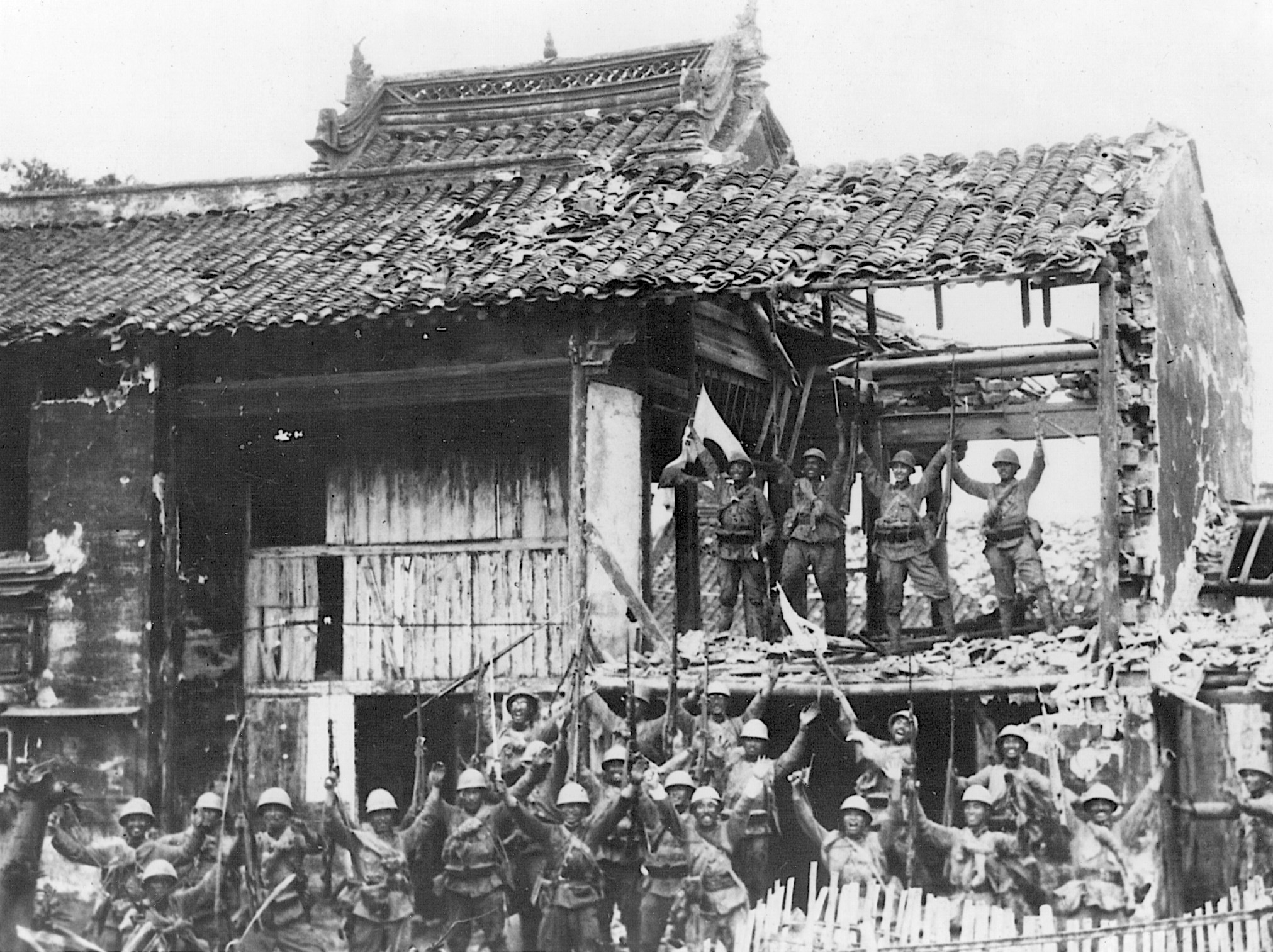 Celebrating their victory in Shanghai on October 21, 1937, Japanese soldiers shout a triumphant “Banzai” from the hollow of a bombed-out building.