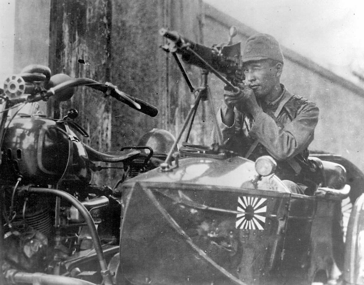 In September 1937, a Japanese soldier aims his machine gun menacingly down a Shanghai street.