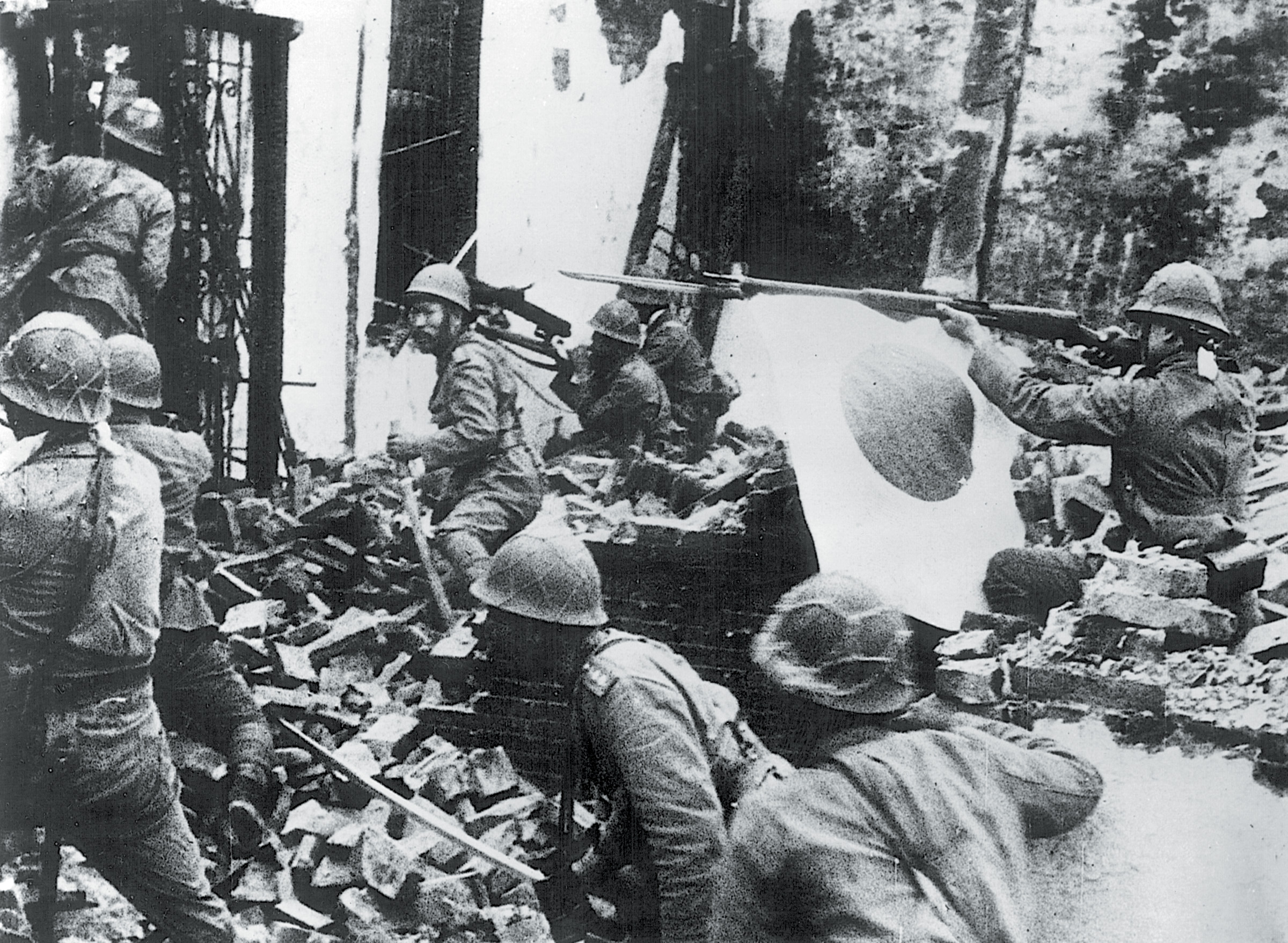 Japanese troops advance through the rubble of a destroyed building in Shanghai on October 29, 1937. Young Marine Captain Evans Carlson witnessed the onslaught.